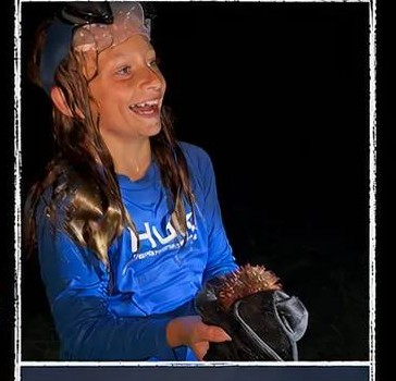 A guest holding a sea urchin she found on a night shelling tour on Siesta Key, Florida